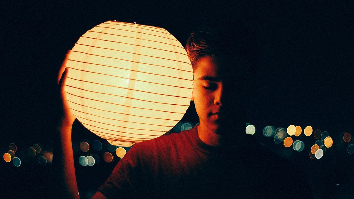 En kille blundar och håller i en rislampa